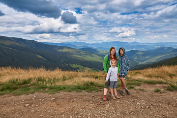 Naklejka premium Portrait of mother with children on a background of mountains. A walk in nature.