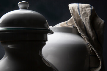 Due vasi in ceramica bianca e uno strofinaccio da cucina su fondo scuro  