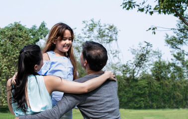 Fototapeta premium Happy cute daughter hugging daddy and mom love isolated on green. Portrait of a happy family of three. Happy family is having fun outdoors. Father, mother and girl are spending