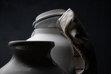 Due vasi in ceramica bianca e uno strofinaccio da cucina su fondo scuro  
