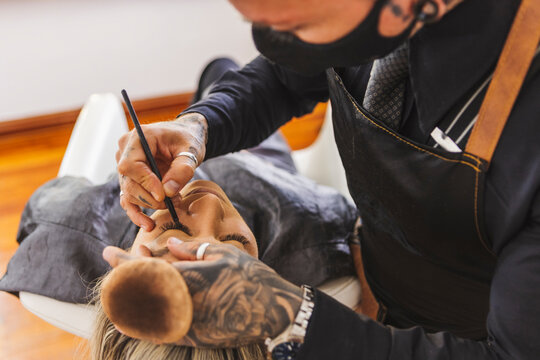 Male visagiste applying eyeliner during on eyelids of model
