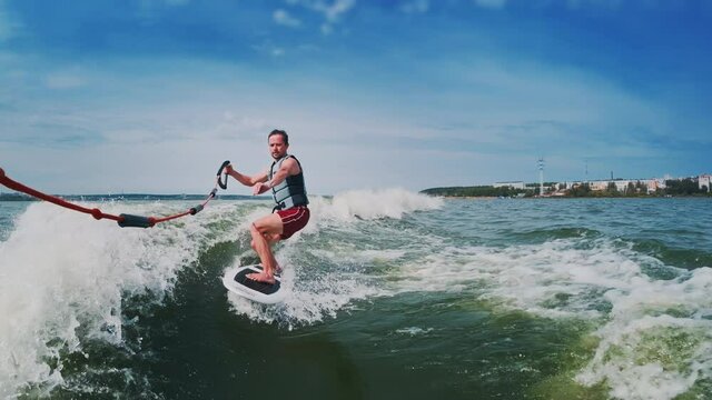 Wakesurfer rides the wake and falls. Time warped footage with extreme slow motion part