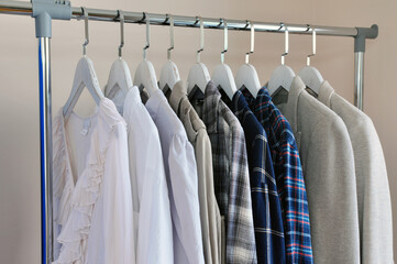 Close up rack with clothes after dry cleaning near light wall