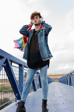 Gay man with rainbow flag listening to music in headphones