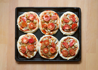Mini pizza. Six pieces of pizza before baking. Baking tray with blanks, before placing in the oven.