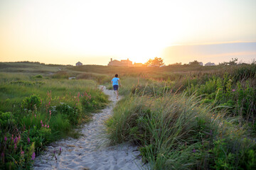 Boy running on a sandy path at sunset