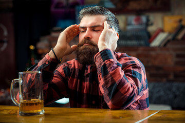 Stressed man drinking beer at pub. Alone bearded man sitting at the bar counter.