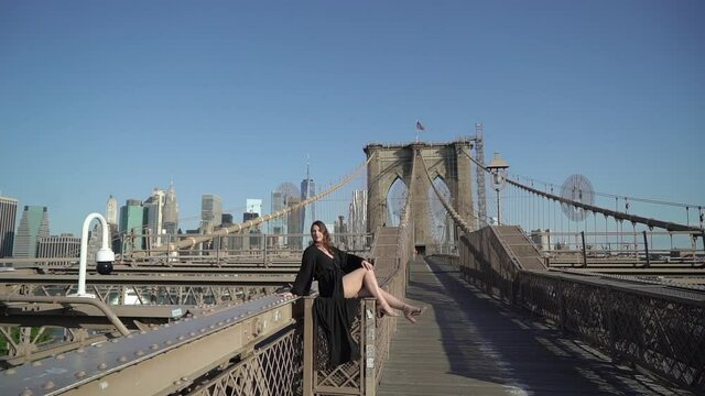 Girl in black long flying dress on Brooklyn Bridge in New York. Posing for photo