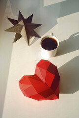 White mug of hot coffee on the white window sill with red heart and star in sun ligh. Having weekend time for yourself. Harmony with yourself. Flat lay, top view