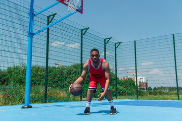 Young african american man playing basketball and looking at camera on playground