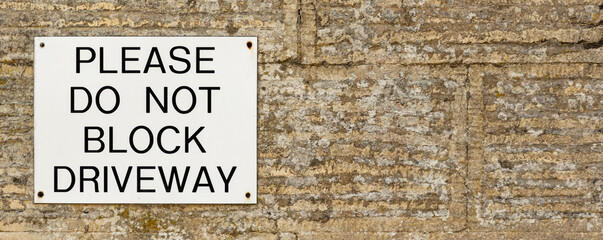 Do Not Block Driveway sign on stone wall, background banner image