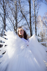 A beautiful angel by the river in winter against the blue sky