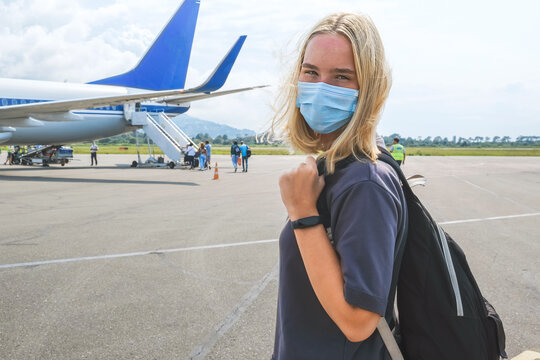 Traveling by plane. Woman tourist boarding a plane for relaxation wearing a face mask. Tourism in the covid pandemic,
