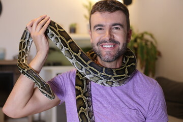Man with large Burmese python at home