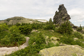 large kurum stones lie in the forest in the mountains, stones covered with moss, against the background of the forest, mountain landscape, high in the mountains.