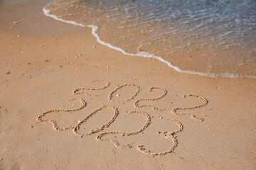 2022 and 2023 written on sand at beach. New Year celebration