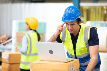 engineer or factory worker using laptop computer and thinking of something seriously in warehouse storage