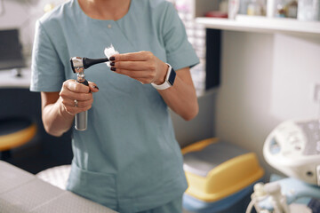 Fototapeta na wymiar Veterinarian cleans otoscope after exanining patient in light office of clinic closeup