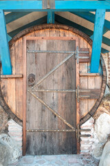 Old wooden grunge brown door with iron door handle on a large barrel