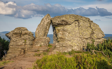 rock 'stone window' on top of a hill at sunset