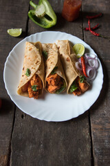 Tortilla or chicken wraps made out of flat bread with chunks of chicken pieces and vegetables stuffed.