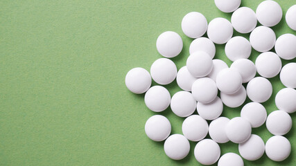 The pills are scattered on the table. Tablets on the green background. Medicinal tablets, capsules.