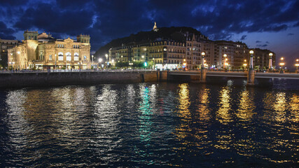 Obraz premium San Sebastian, Spain - 29 Aug 2021: Lights of the old town buildings reflect on the Urumea River