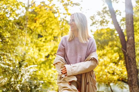 Caucasian Blonde Woman Smiling Happily On Sunny Autumn Or Spring Day Outside Walking In Park.