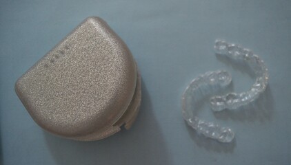 Invisible tooth braces or retainers on a blue background symbolizing orthodontic post-treatment