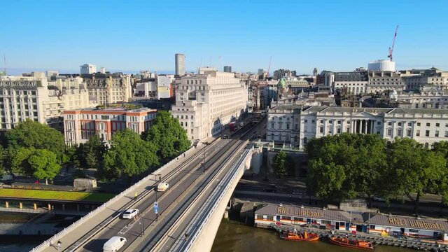 Crane down footage of bridge over Thames river and Somerset House on waterfront. Scene lit by bright morning light. London, UK