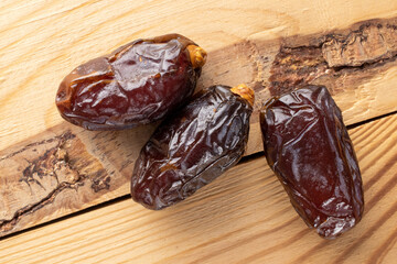Three royal dates on a wooden table, close-up, top view.