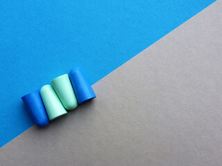 Green and blue earplugs on blue and gray background