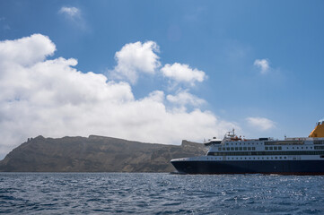 Cruise ship near Santorini island in Aegea sea, Greece. Ferry sailing to port. Transportation by...