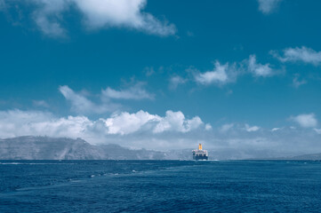 Fototapeta premium Cruise ship near Santorini island in Aegea sea, Greece. Ferry sailing to port. Transportation by sea.