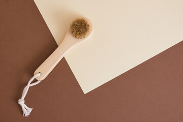 wooden brush with natural bristles for dry face massage on brown and beige background