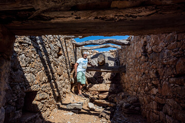 a man in green against the background of ancient dilapidated mills on the island of Crete 