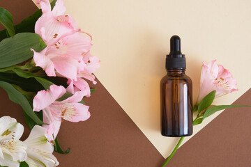 Amber glass bottle on a neutral background with a lily flowers. copy space. Cosmetic, skin care concept