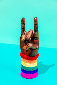 Hand with horn gesture and LGBTQ ornament on wristband