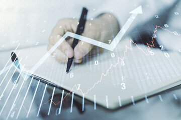 Abstract creative financial graph with upward arrow and man hand writing in diary on background, financial and trading concept. Multiexposure