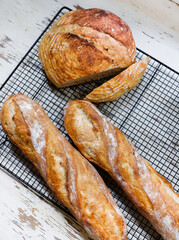 Fresh baked bread and baguettes on a cooling rack in a bakery.