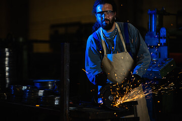 Heavy industry worker cutting steel with an angle grinder.