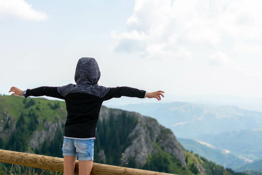 Pretten girl standing on top of a mountain with raised hands. Back view of Happy excited girl winner traveler raising arms up to blue sky. freedom concept. copy space.