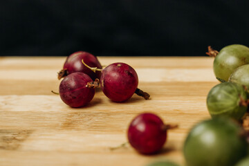 Gooseberry. Red and green gooseberries. Gooseberries on a wooden surface.