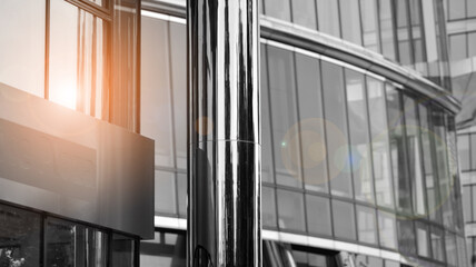 Obraz premium Modern architectural details. Modern glass facade with a geometric pattern. Contemporary corporate business architecture. Red sun on horizon. Black and white toned image.