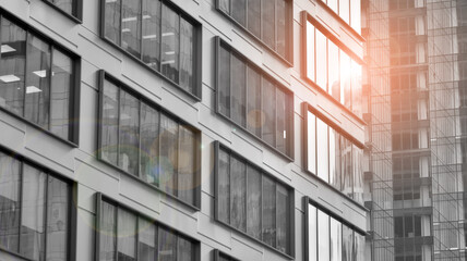 Obraz premium Modern architectural details. Modern glass facade with a geometric pattern. Contemporary corporate business architecture. Red sun on horizon. Black and white toned image.