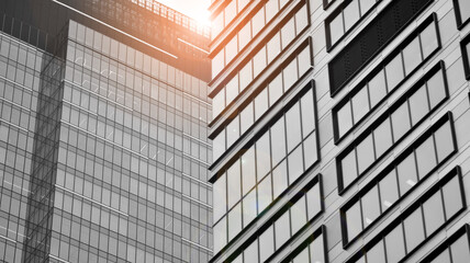 Fototapeta na wymiar Modern architectural details. Modern glass facade with a geometric pattern. Contemporary corporate business architecture. Red sun on horizon. Black and white toned image.