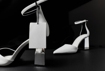 High-heeled silver shoe lying on black wavy satin fabric. Women's shoes for party. Shopping concept.