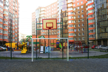 The  sports ground  and stadium nearby of a tall building. Handball gate and a basketball backboard in the center. against the background of the high-rise.