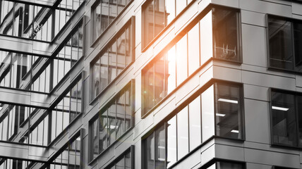 Modern architectural details. Modern glass facade with a geometric pattern. Contemporary corporate business architecture. Red sun on horizon. Black and white toned image.