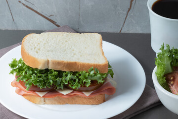 Loaf bread stuffed with lettuce, tomato, cheese and mortadella served with coffee.